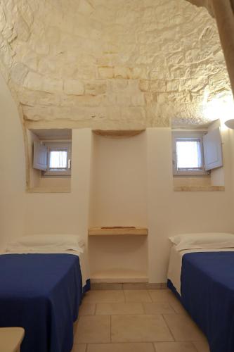 two beds in a room with two windows at I trulli di Nonno Battista in Locorotondo