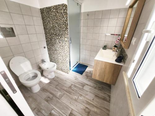 Un baño con inodoro, lavabo y ducha. en Casa al mare Orchidea - Motoparking - Wifi Free - AC, en Cala Gonone