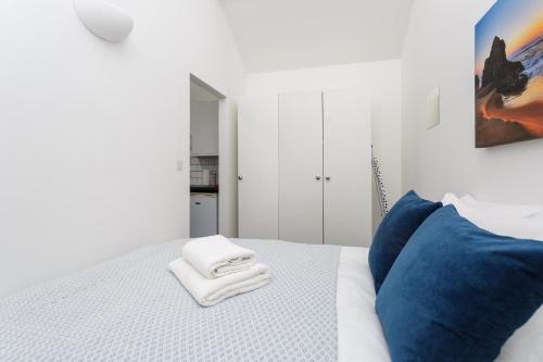 a white bedroom with a bed with blue pillows at Stylish Self-Contained Annex near City Centre in Southampton
