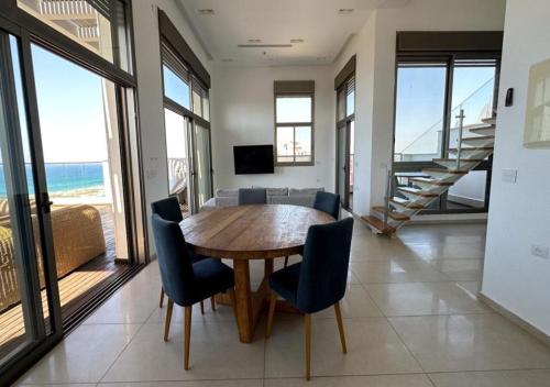 una sala da pranzo con tavolo in legno e sedie blu di הקומה ה 16 POOL PENTHAUSE a Hadera