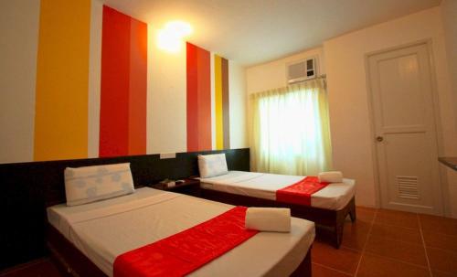 a room with two beds and a colorful wall at Travelbee Heritage Inn in Dapitan