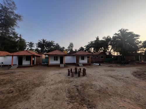 a group of houses with trees in the background at Revibe Beach Hostel Gokarna in Gokarna