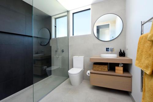 ein Badezimmer mit einem WC, einem Waschbecken und einem Spiegel in der Unterkunft Harakeke Boutique Accommodation in Mahana