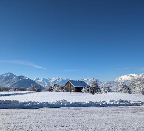 a house in a snowy field with mountains in the background at Apartment - Über den Wolken in Batschuns