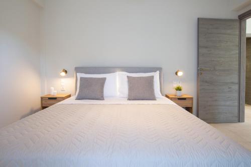 a bedroom with a large white bed with two tables at Amelie's Luxe Apartments in Lefkada Town