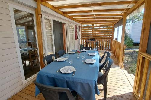 una mesa con sillas y un mantel azul en un porche en 490 Emplacement luxe aux Dunes de Contis 3*, en Saint-Julien-en-Born