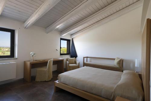 a bedroom with a bed and a desk and windows at Solea Relais di Charme- Adults only in Trecastelli