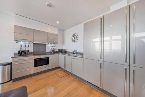 a kitchen with white cabinets and a clock on the wall at Great 2 Bed Flat With City View in London