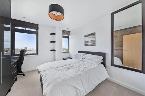 a bedroom with a bed and a desk and a window at Great 2 Bed Flat With City View in London