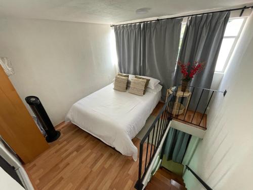 メキシコシティにあるMini Loft en Coyoacánのベッドと窓が備わる小さな客室です。