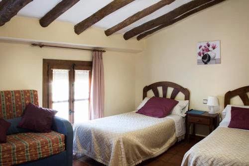 a bedroom with two beds and a couch and a window at Pension Las Cuevas de Cañart in Las Cuevas de Cañart