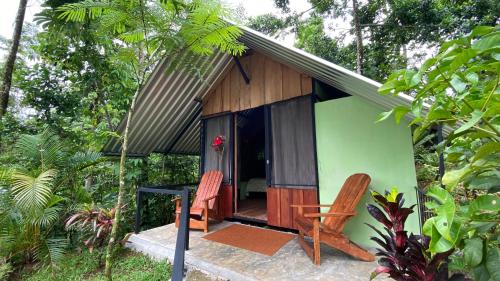 une petite maison verte en bois avec 2 chaises dans l'établissement Guapote Lodge, à Tigra