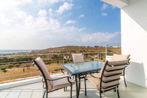 una mesa y sillas en un balcón con vistas al océano en Aegean colors Tinos en Tinos Town