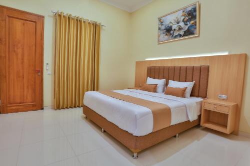 1 dormitorio con 1 cama grande y cabecero de madera en The Horizontal Hotel Pacitan, en Pacitan