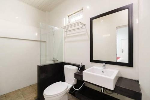 a bathroom with a white toilet and a sink at RedDoorz Plus near Palembang Icon Mall 2 in Palembang