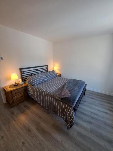 a bedroom with a bed and a nightstand with a lamp at Superbe condo face aux pentes de ski Stoneham!!! in Stoneham