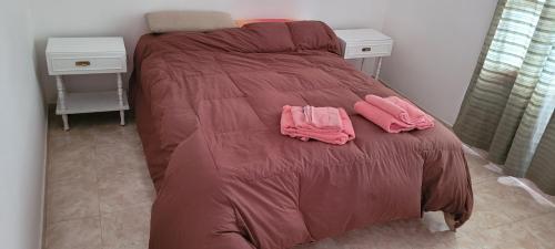 Una cama con dos toallas rosas encima. en ALOJAMIENTOS BJ en Puerto San Julián