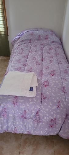 Una cama con colcha púrpura con ladillas de cangrejo. en ALOJAMIENTOS BJ en Puerto San Julián