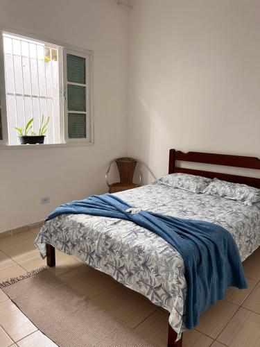 Una cama en un dormitorio con una manta azul. en Casa Bela en Praia Grande