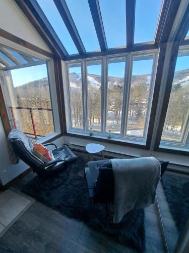 a living room with windows and a table and chairs at Superbe condo face aux pentes de ski Stoneham!!! in Stoneham