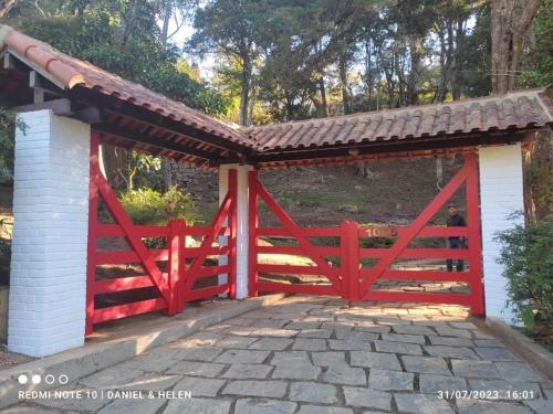 a red bridge with a wooden gate and a fence at Pousada Motta in Miguel Pereira