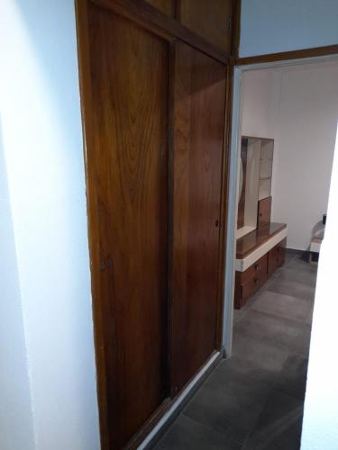 een houten kast in een kamer met een spiegel bij LeoDiMar Depto 7 in Villa Gesell