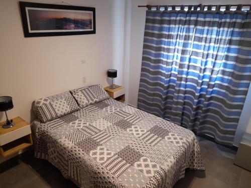 een slaapkamer met een bed en een blauw gordijn bij LeoDiMar Depto 7 in Villa Gesell