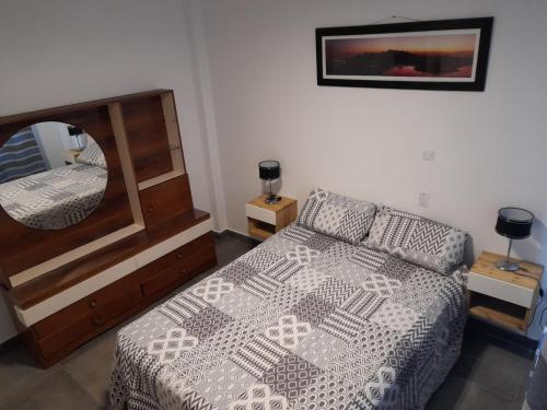 een slaapkamer met een bed en een spiegel bij LeoDiMar Depto 7 in Villa Gesell