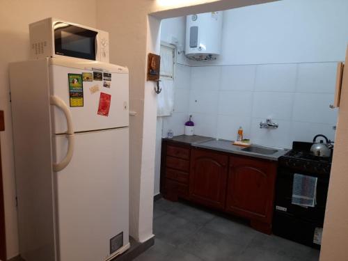 een keuken met een witte koelkast en een fornuis bij LeoDiMar Depto 7 in Villa Gesell