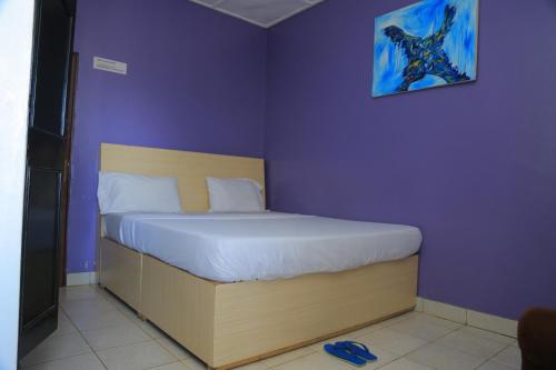 Bett in einem Zimmer mit lila Wänden in der Unterkunft Stunning 6-Bed Apartment in Kigali in Kigali