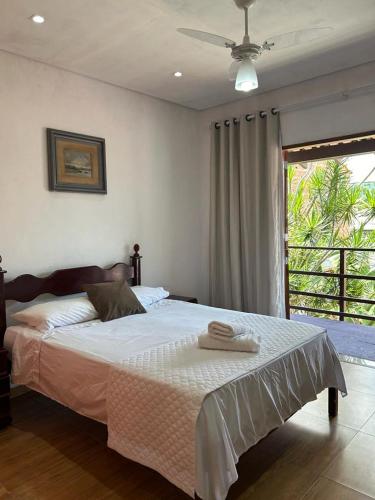 a bedroom with a large bed with a ceiling fan at Casa Eliane in Paraty