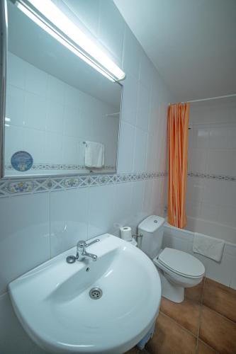 a bathroom with a sink and a toilet and a mirror at Pension Las Cuevas de Cañart in Las Cuevas de Cañart