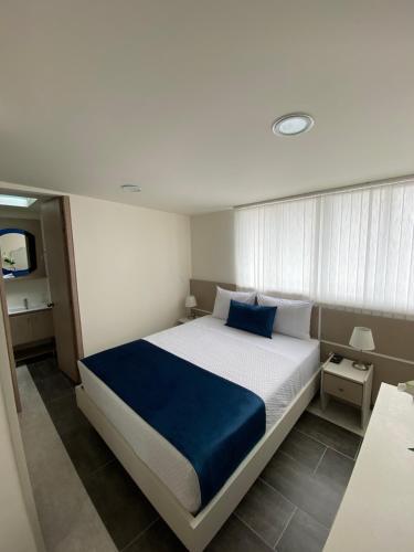 a bedroom with a large bed with a blue blanket at Hotel Boutique Paralela Real. in Manizales