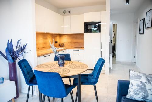 a kitchen and dining room with a table and blue chairs at Apartamenty Belni Hel Edyta i Maciej Wolak in Hel