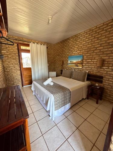 ein Schlafzimmer mit einem Bett in einer Ziegelwand in der Unterkunft Pousada Catavento in Flecheiras