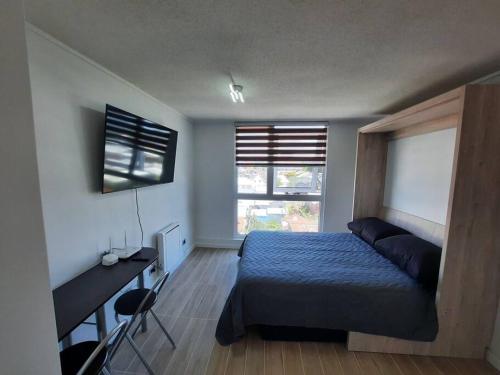 1 dormitorio con cama, escritorio y ventana en Departamento en Valdivia. en Valdivia