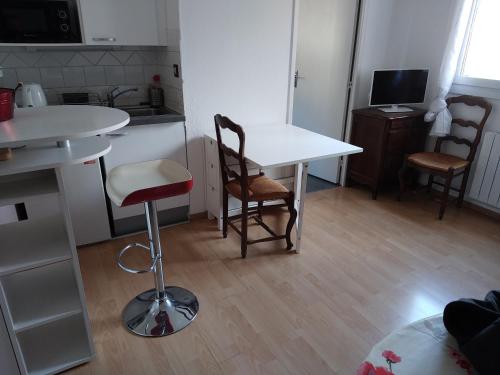 Il comprend une petite cuisine avec une table et des chaises blanches. dans l'établissement Studio 25 m2 centre Uriage - tarif pour curistes, à Saint-Martin-dʼUriage