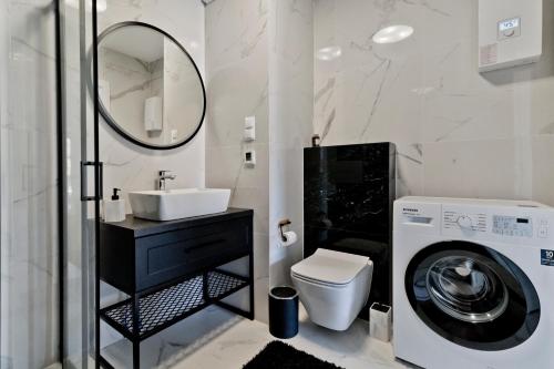 a bathroom with a sink and a washing machine at Apartamenty Belni Hel Edyta i Maciej Wolak in Hel