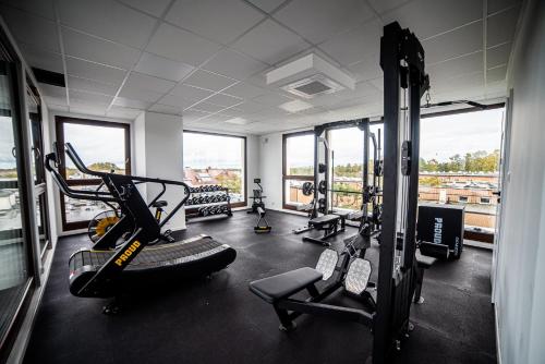 a gym with treadmills and machines in a room with windows at Apartamenty Belni Hel Edyta i Maciej Wolak in Hel