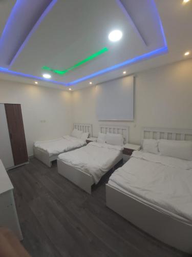 um quarto com duas camas e uma luz azul em شقة واسعة و أنيقة em Quaniya