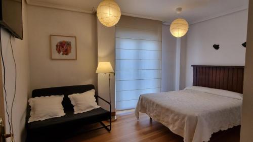 a bedroom with a bed and a chair and lights at Sol y Nieve Campoo in Reinosa