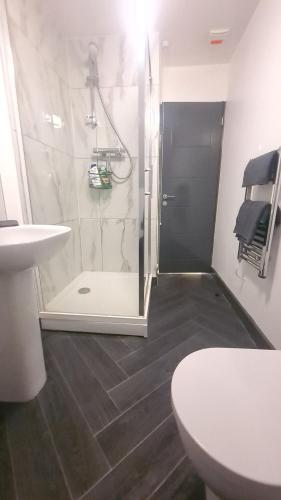 een badkamer met een douche, een toilet en een wastafel bij Homestay by BIC Oates 9 in Dewsbury