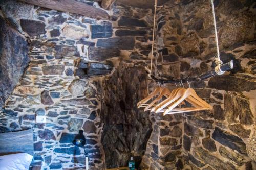 a stone wall with wooden utensils hanging on it at Cabo Do Mundo Casa Rural in Chantada