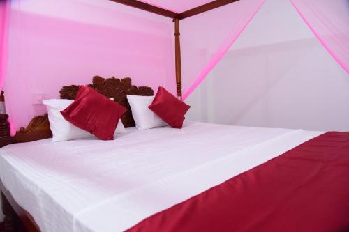 a bed in a tent with red and white pillows at GK Home Stay in Hikkaduwa