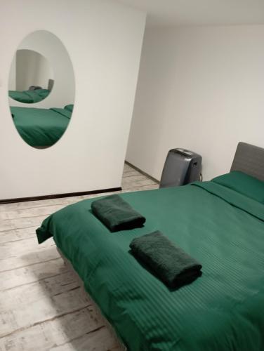 - une chambre avec un lit vert et un miroir dans l'établissement PENSIUNE Sweet Touch, à Craiova