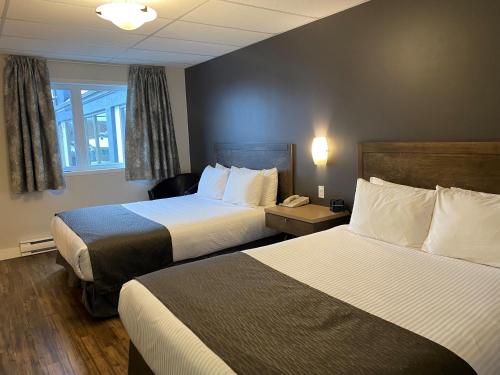 a hotel room with two beds and a phone at Hôtel Centre-Ville in Montmagny