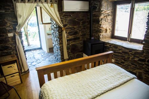 a bedroom with a wooden bed and a stone wall at Cabo Do Mundo Casa Rural in Chantada