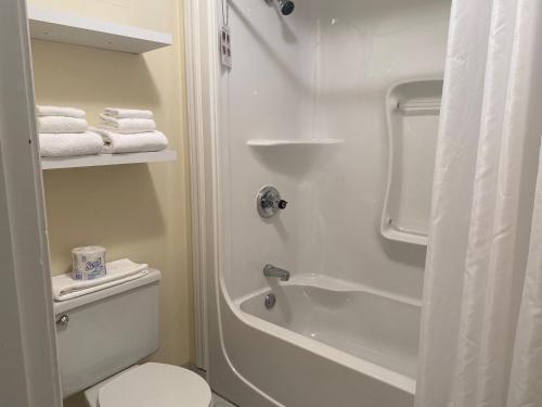 a bathroom with a toilet and a shower with towels at Hôtel Centre-Ville in Montmagny