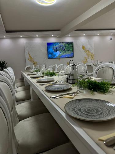 a long dining room with white chairs and a long table at Conacul Peștera Urșilor in Chişcău