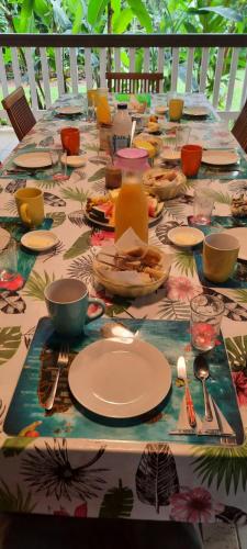 een lange tafel met borden en bestek erop bij Villa Kannel in Petit-Bourg